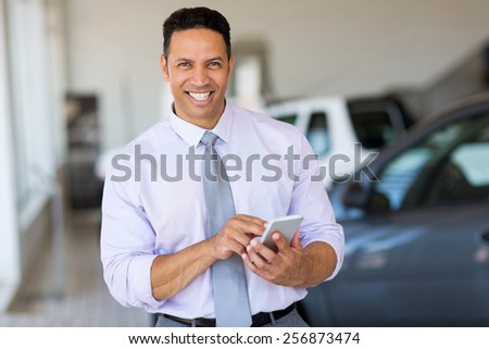 handsome middle aged man using smart phone at car dealership