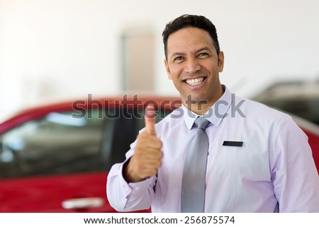 handsome car salesman thumb up at car dealership