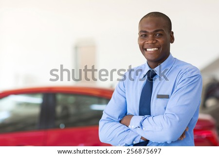portrait of african american car sales consultant with arms folded in showroom