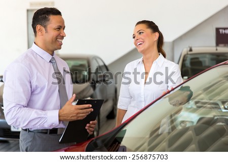 middle aged car salesman talking to a customer in showroom