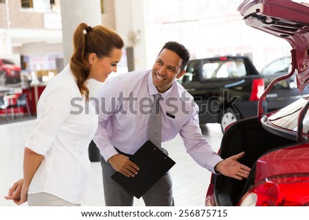 handsome car salesman showing new vehicle to customer