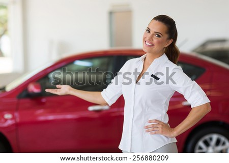 happy young saleswoman welcoming gesture in car showroom