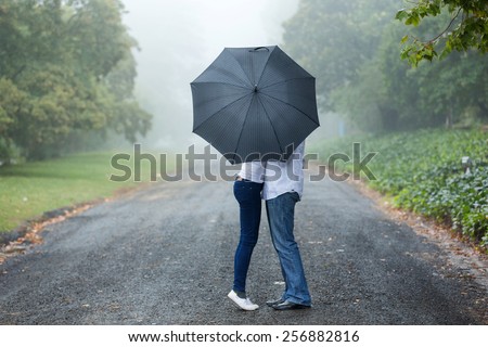 couple kissing behind the umbrella in the mist