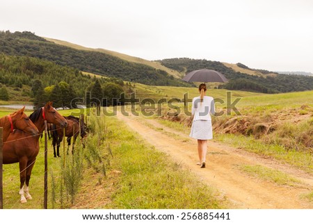 back view of young woman walking on farm road