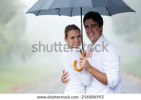 happy young couple holding an umbrella in the rain