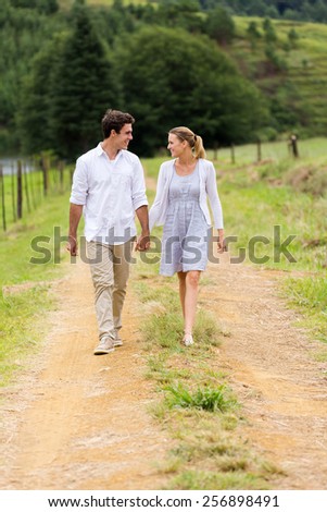 happy couple holding hands walking in countryside