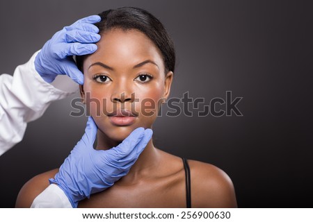 dermatologist checking pretty african woman face skin