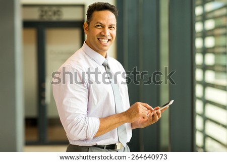 happy middle aged business executive using smart phone in office