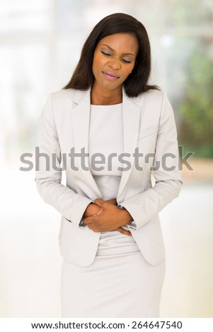young african woman having stomach ache in office
