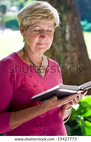 elderly woman reading bible in the garden