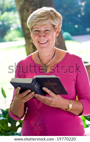 elderly woman reading a bible outdoors