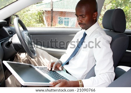 african businessman using laptop computer in a car