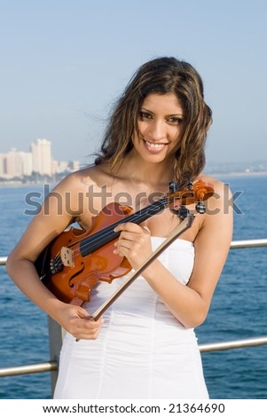 happy indian woman play violin on beach pier