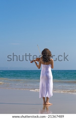 beautiful young indian woman play violin on beach