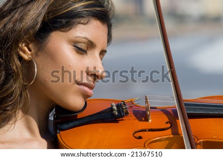 beautiful young indian woman play violin on beach