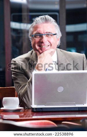Portrait of a happy senior business man sitting by his laptop