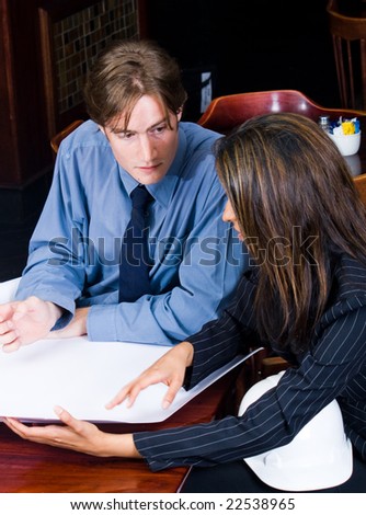 A handsome business construction manager and indian female construction worker in a cafe looking at blueprint