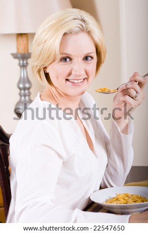 young blond beautiful woman sitting by breakfast table with cereal and milk