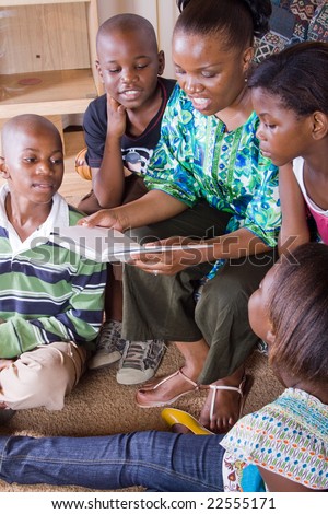 a happy african mother reading a book to her 4 children in living room