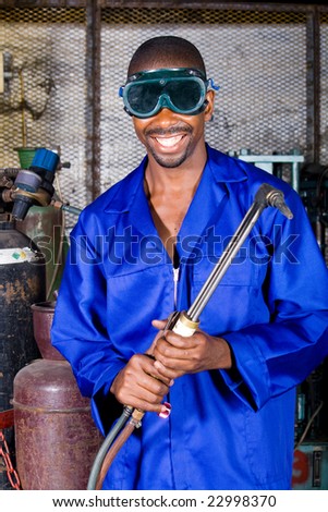 african male welder with protective goggles and gas welding machine