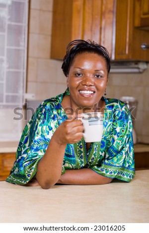 happy african woman drinking coffee in the kitchen