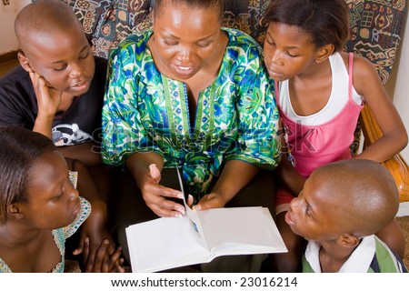 a happy african mother reading a book to her 4 children in living room