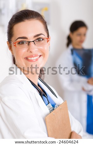 smiling female beautiful doctor in hospital, background is her colleagues