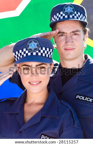 two south africa police officer saluting in front of south african flag
