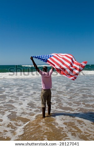 young african american man waving a USA flag on beach