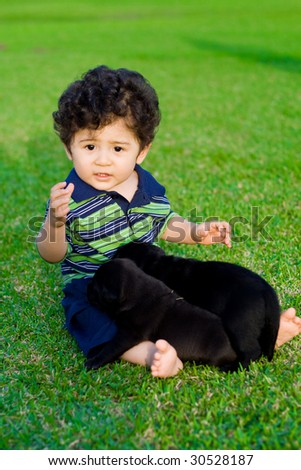 cute baby boy playing with little black chow puppy