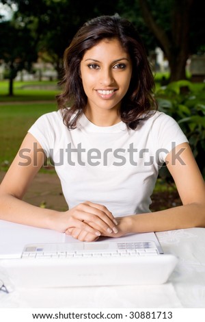 beautiful young indian woman smiling outdoors with laptop
