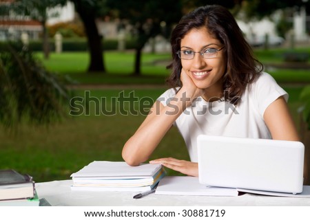 cheerful young indian college student outdoors with laptop