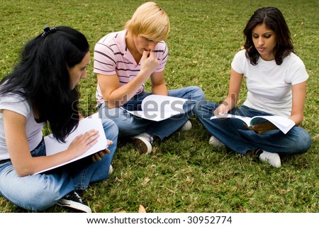 group of college students sitting in circle and reading book in the park