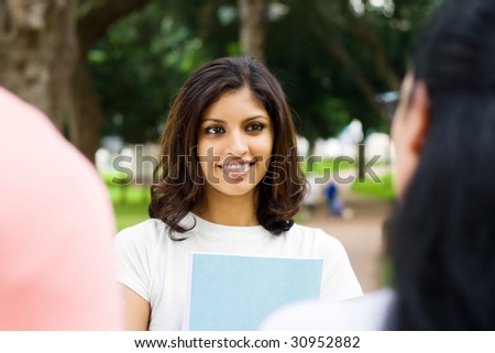 portrait of a happy beautiful indian college student talking to her classmate outdoors