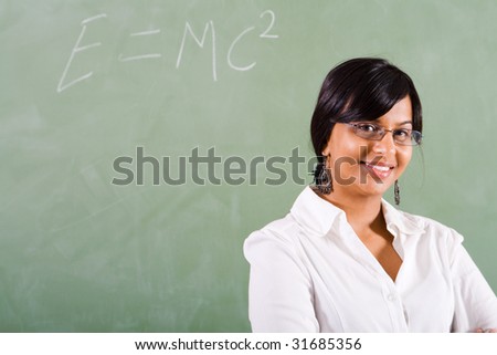 young beautiful school teacher standing in front of blackboard