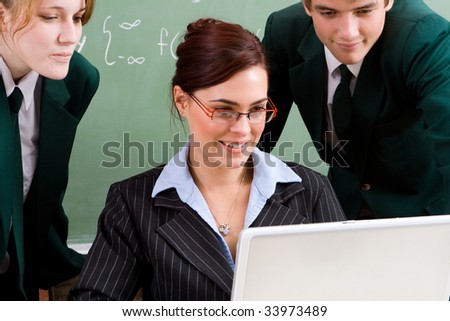 attractive school teacher teaching computer lesson to her students