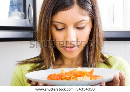young woman smelling warm food in kitchen