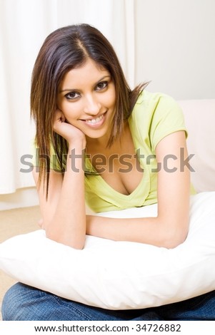young indian woman sitting on bedroom floor with a pillow