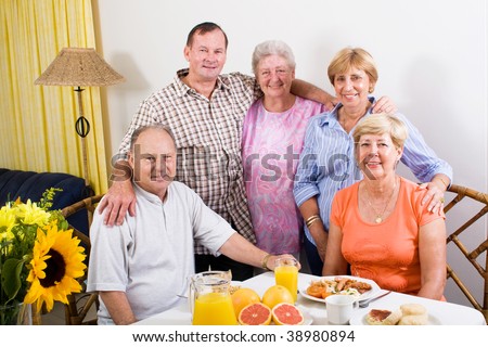group of happy senior friends at breakfast table