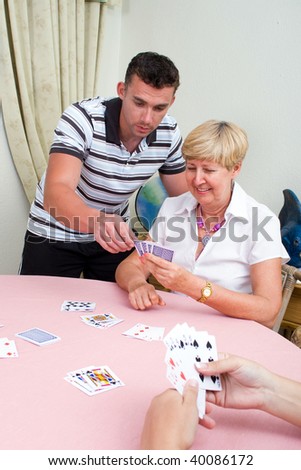 young man teaching senior woman how to play cards