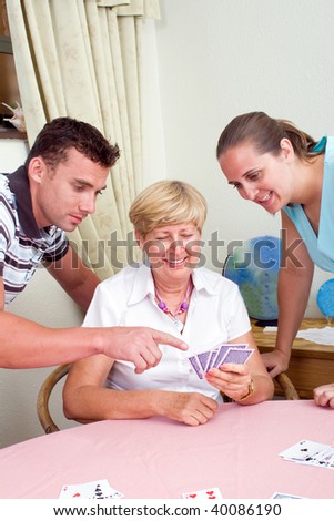 son and daughter teaching senior mother how to play cards