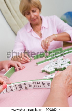 elderly lady playing mahjong game with friends
