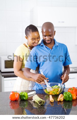 african american couple in kitchen making salad