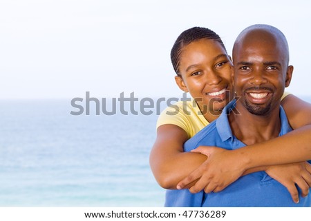 stock photo : young happy african american couple piggyback, background is beautiful sea view