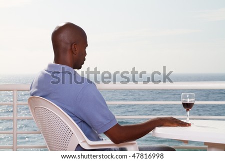 young african american man drinking wine on sea view balcony