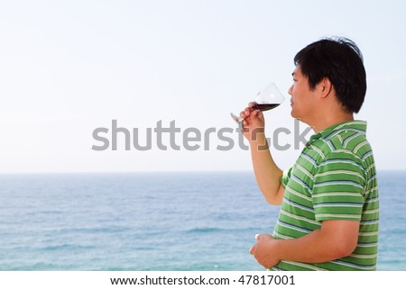 casual chinese man drinking wine and viewing seascape