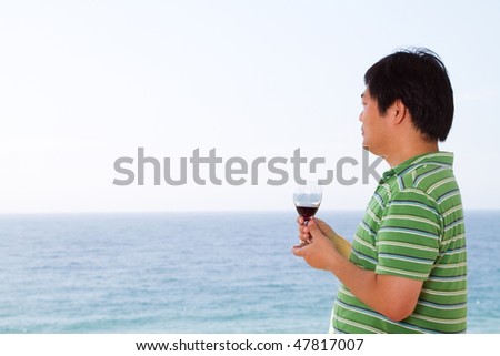 casual chinese man drinking wine and viewing seascape