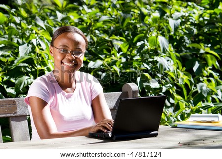 female African American student studying computer outdoors