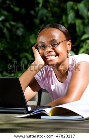 happy african american female student studying computer outdoors