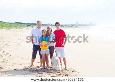 Portrait of Caucasian family of four and their family dog on beach